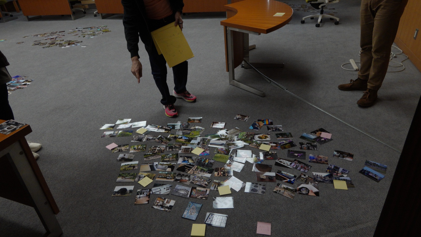 Editors discuss an arrangement of photographs laid out on the floor